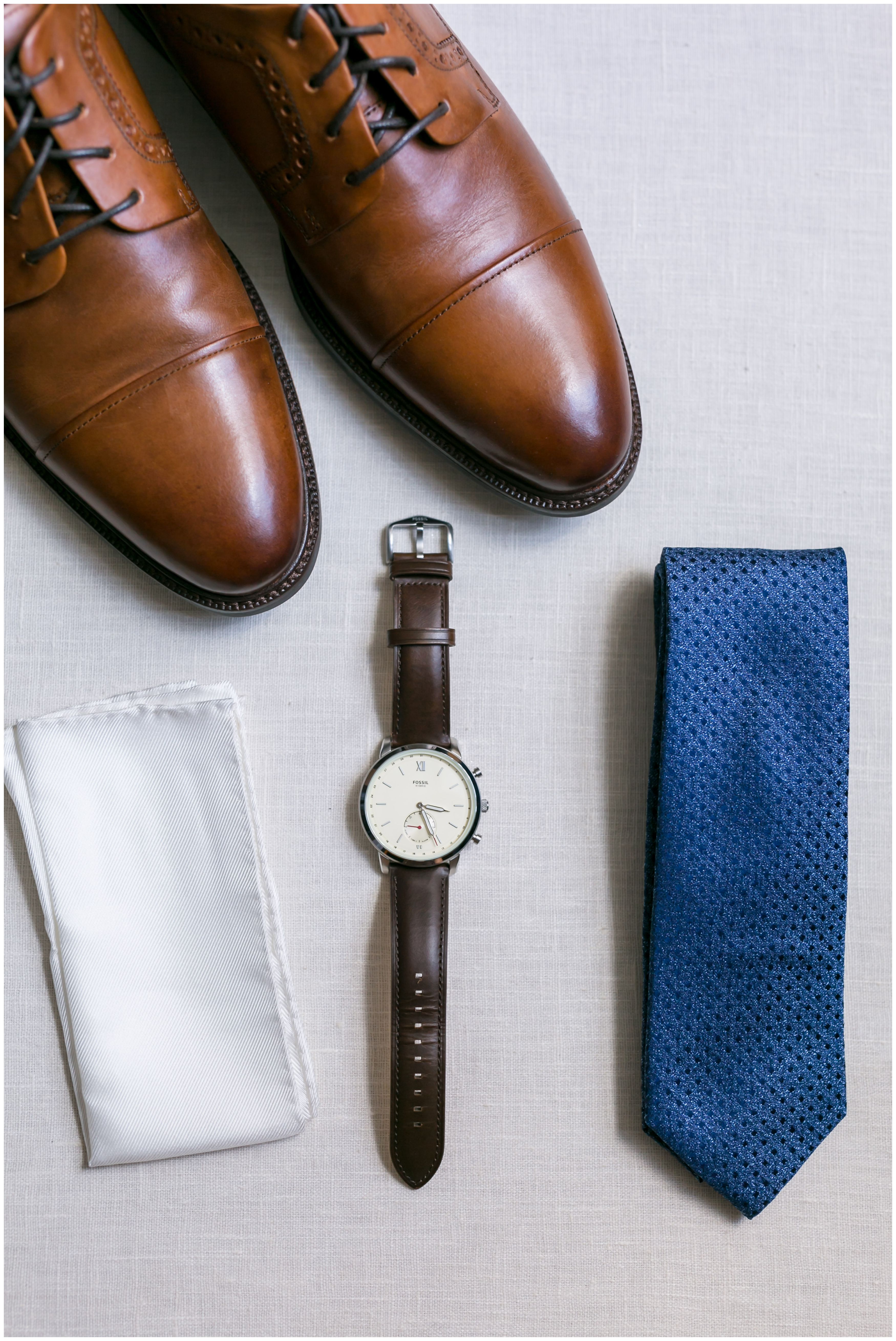 Groom details shoes, white pocket square, brown leather watch, navy tie