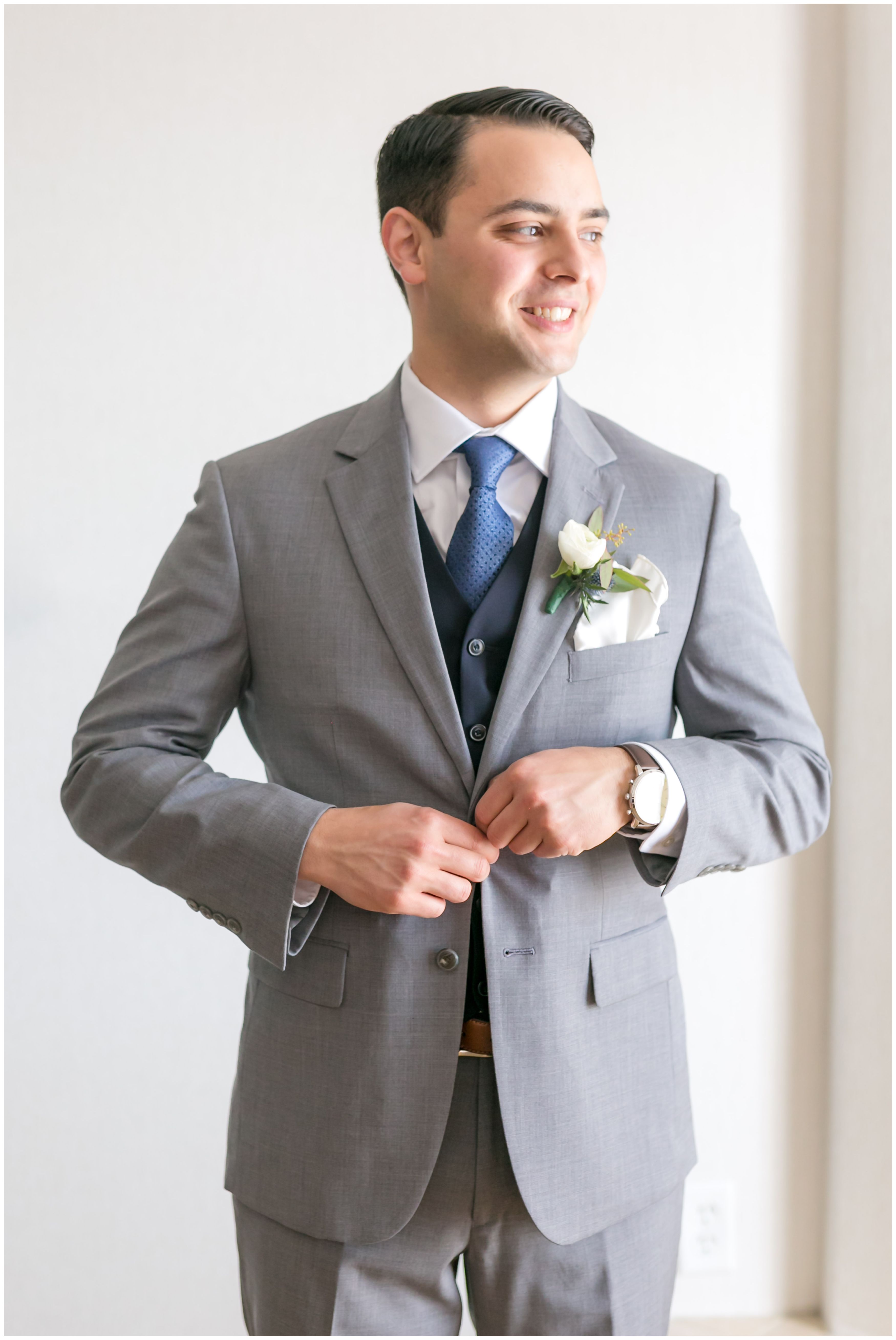 Groom light gray suit with navy vest and tie getting ready