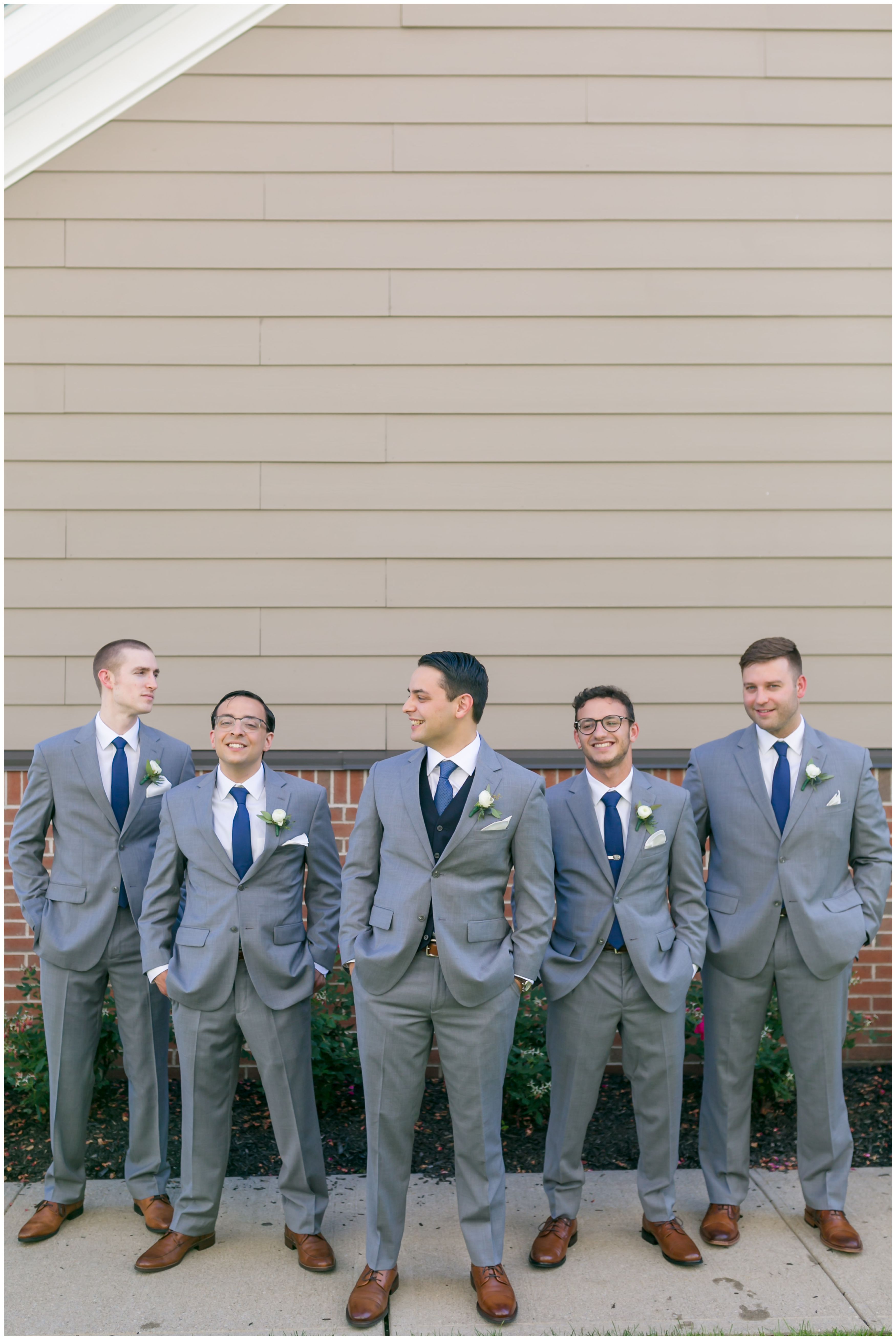 Groom and groomsmen in light grey suits and navy vests and ties