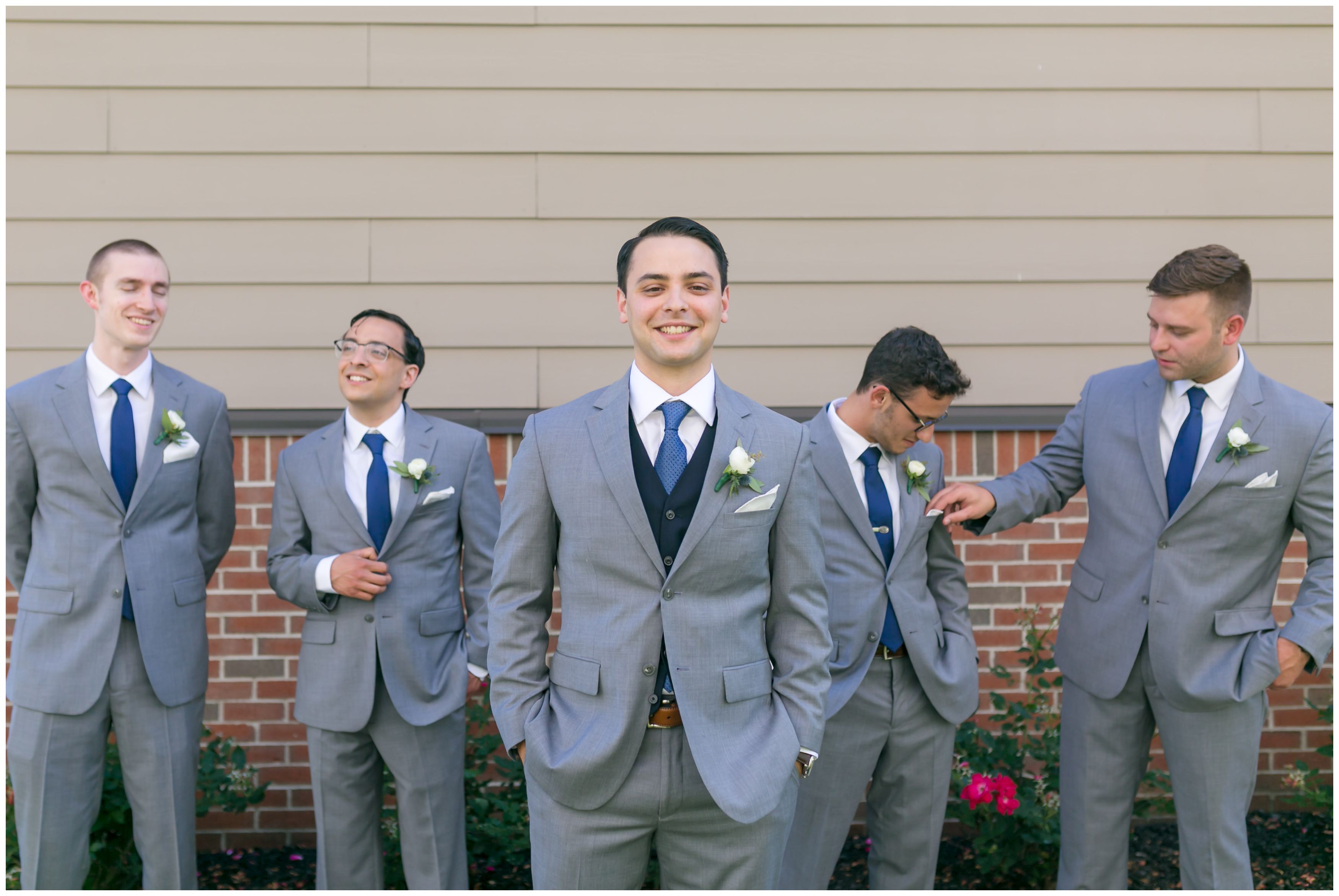 Groom and groomsmen having fun light grey suits and navy blue ties