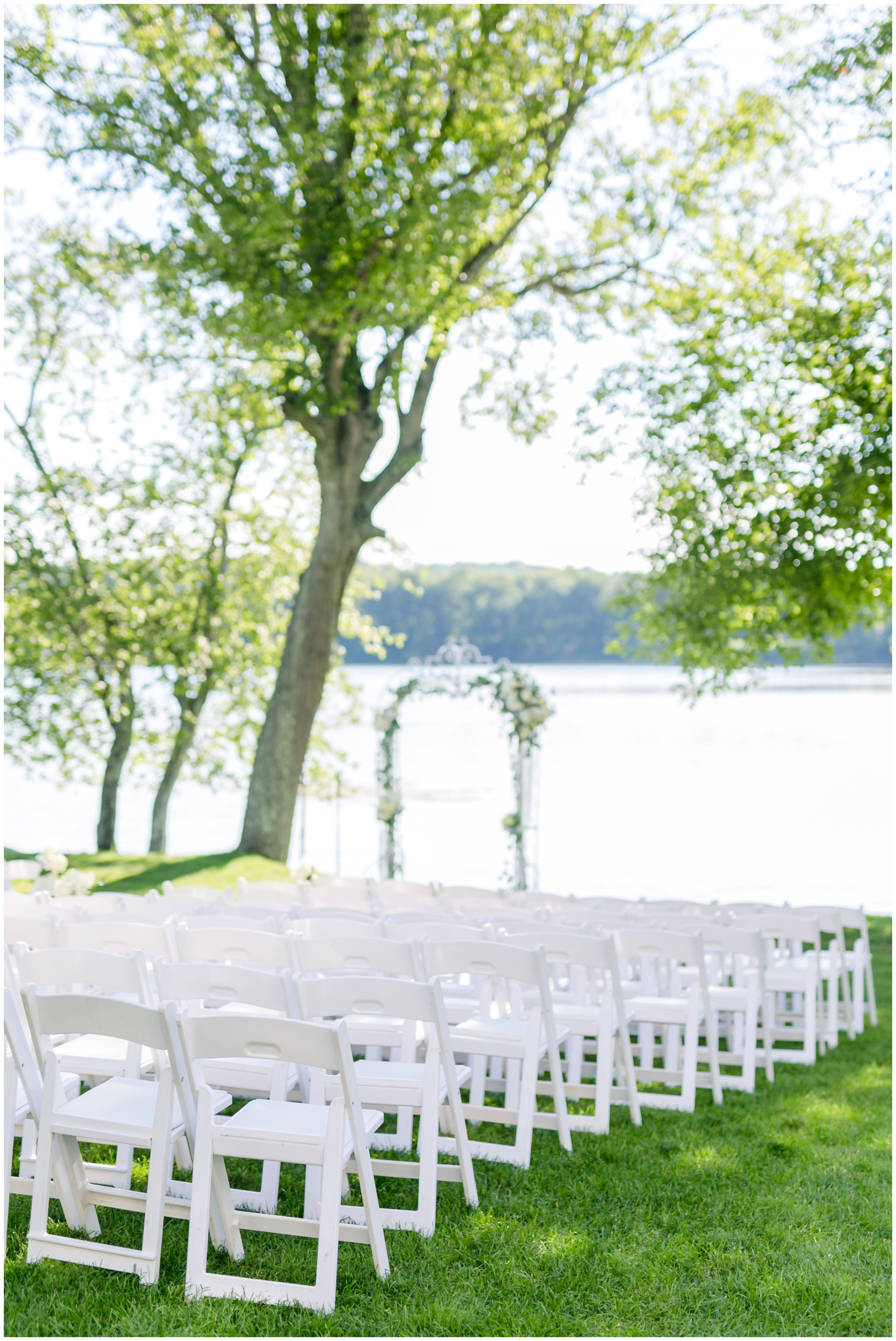 Outdoor lakeside ceremony with white floral ceremony arch