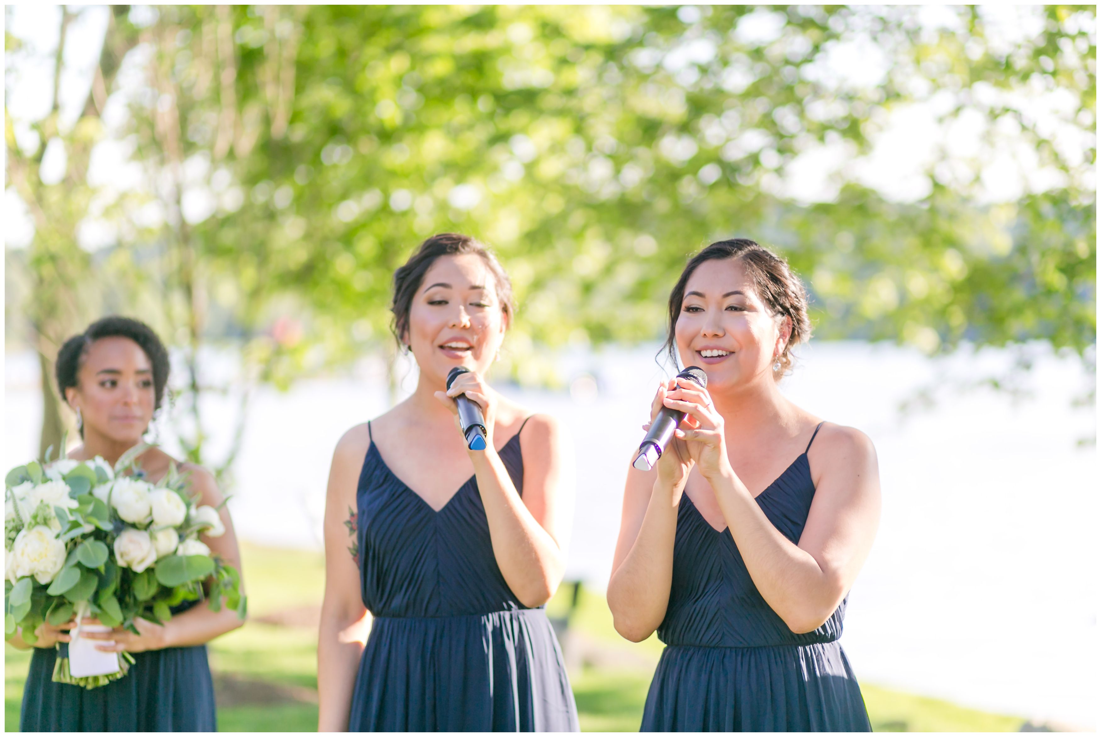 Twin sisters singing at outdoor lakeside ceremony