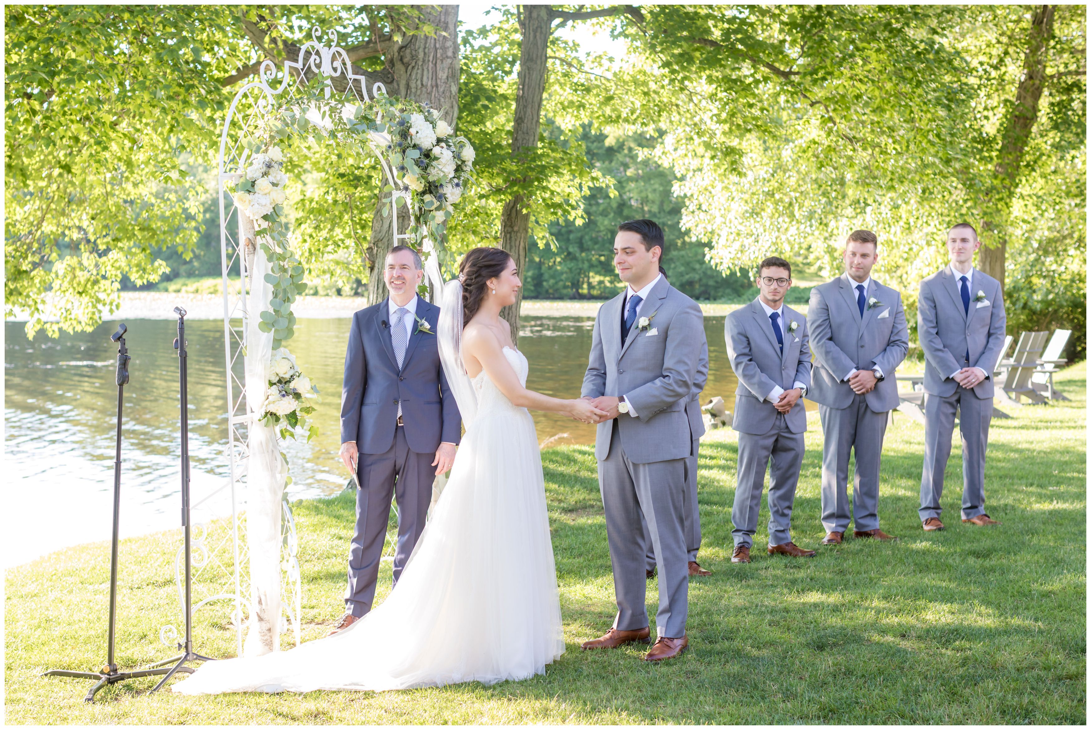 Bride and groom looking at each other during song at outdoor lakeside ceremony