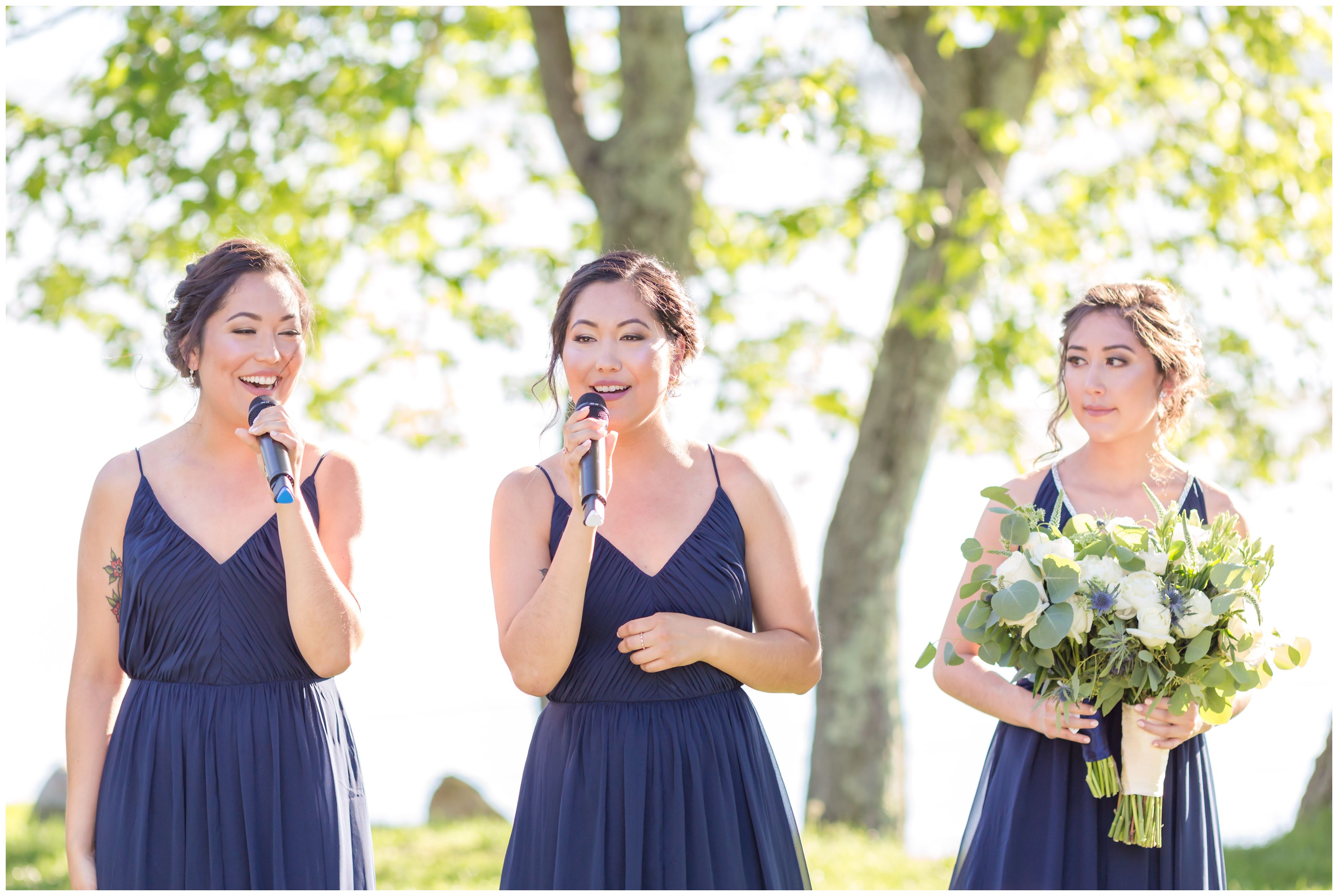 Twin sisters singing song at outdoor lakeside ceremony