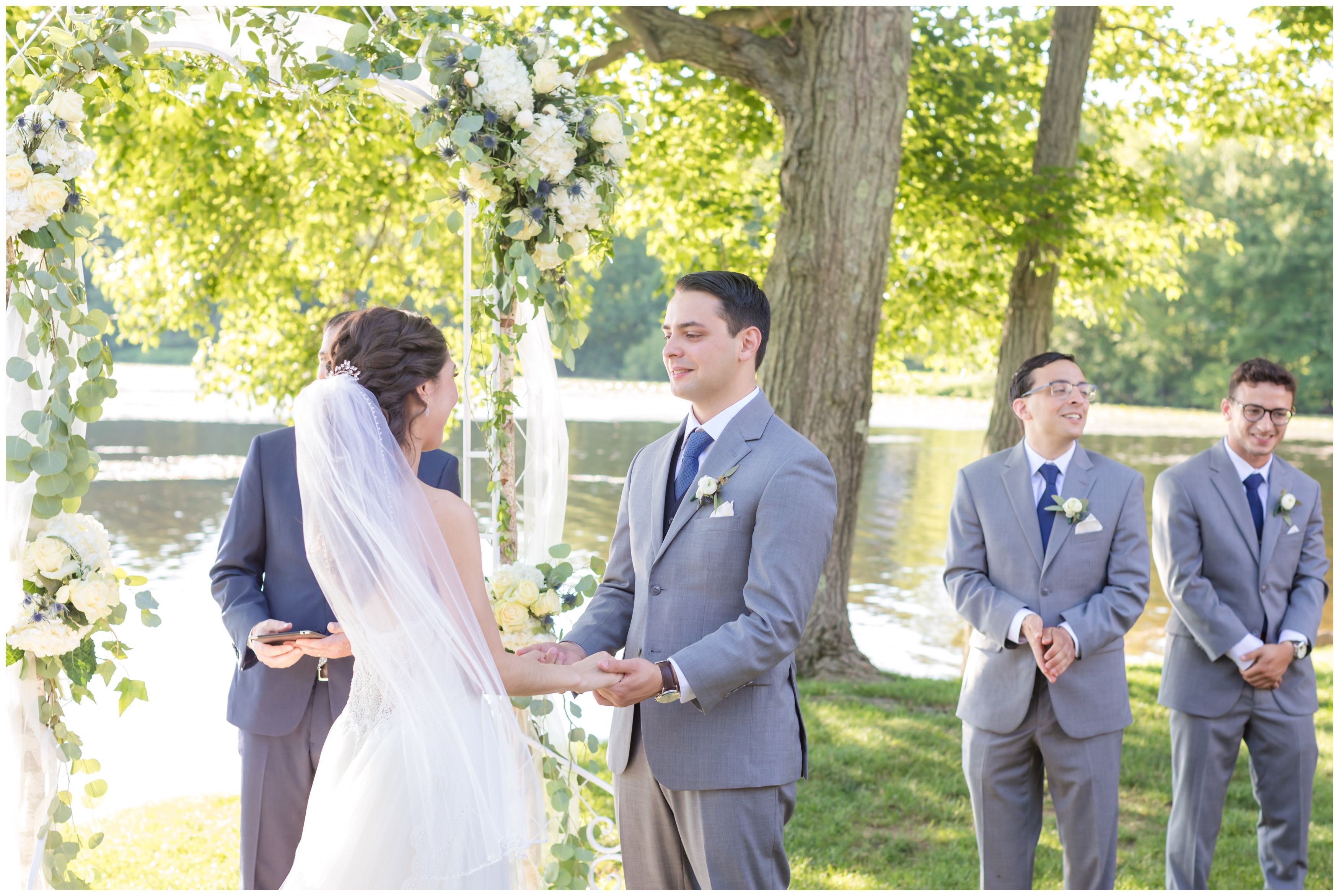 Groom and bride saying vows at outdoor lakeside ceremony